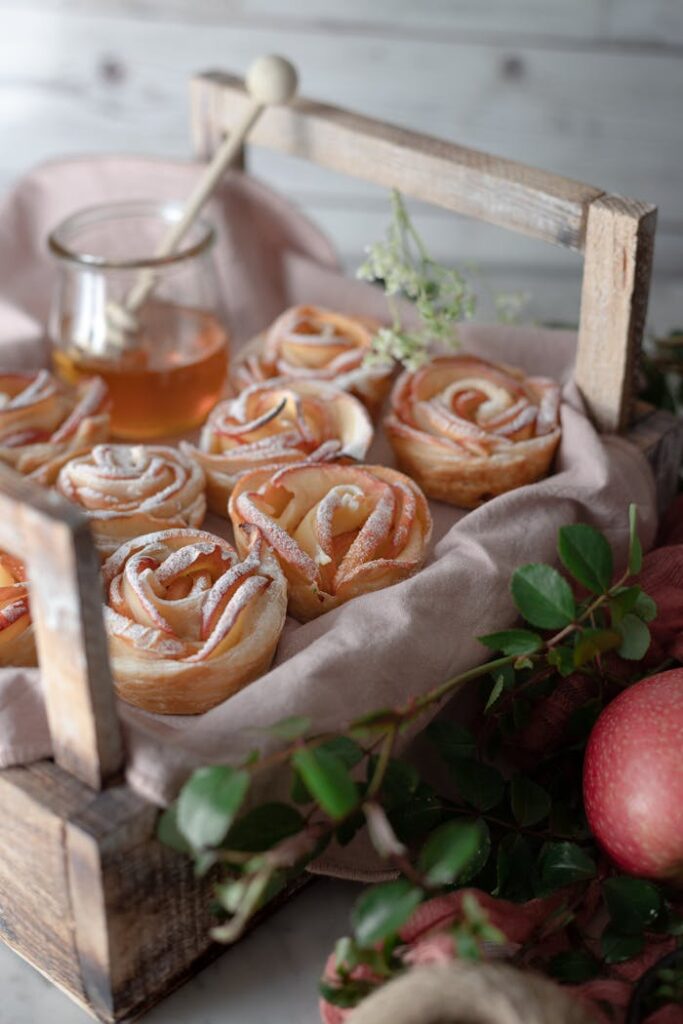 Delicious apple rose pastries beautifully presented with honey and greenery in a rustic setting.